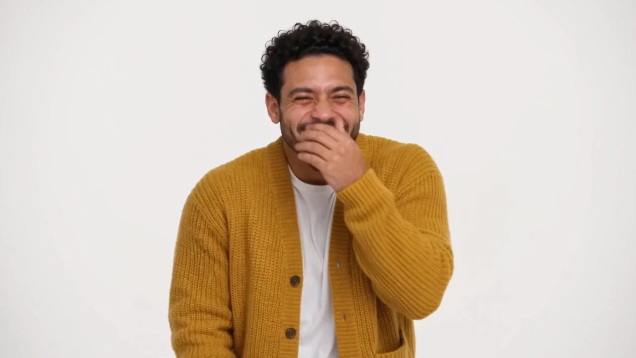 Oh you can make it cap AI video sample: a man in a mustard cardigan laughs behind his hand, then a woman in a green blazer spins in a white studio