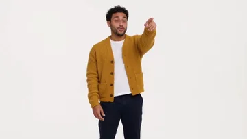 Shot of the sample: the man in the mustard cardigan points at someone off camera