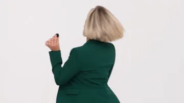 Shot of the sample: the woman in the green blazer spins and looks back