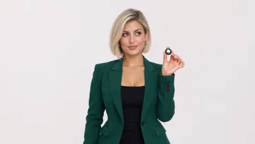 Shot of the sample: the woman holds a small object with a smug look