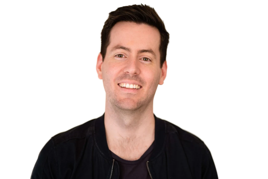A smiling man in a dark jacket with the background removed by the background remover, shown on a red circle