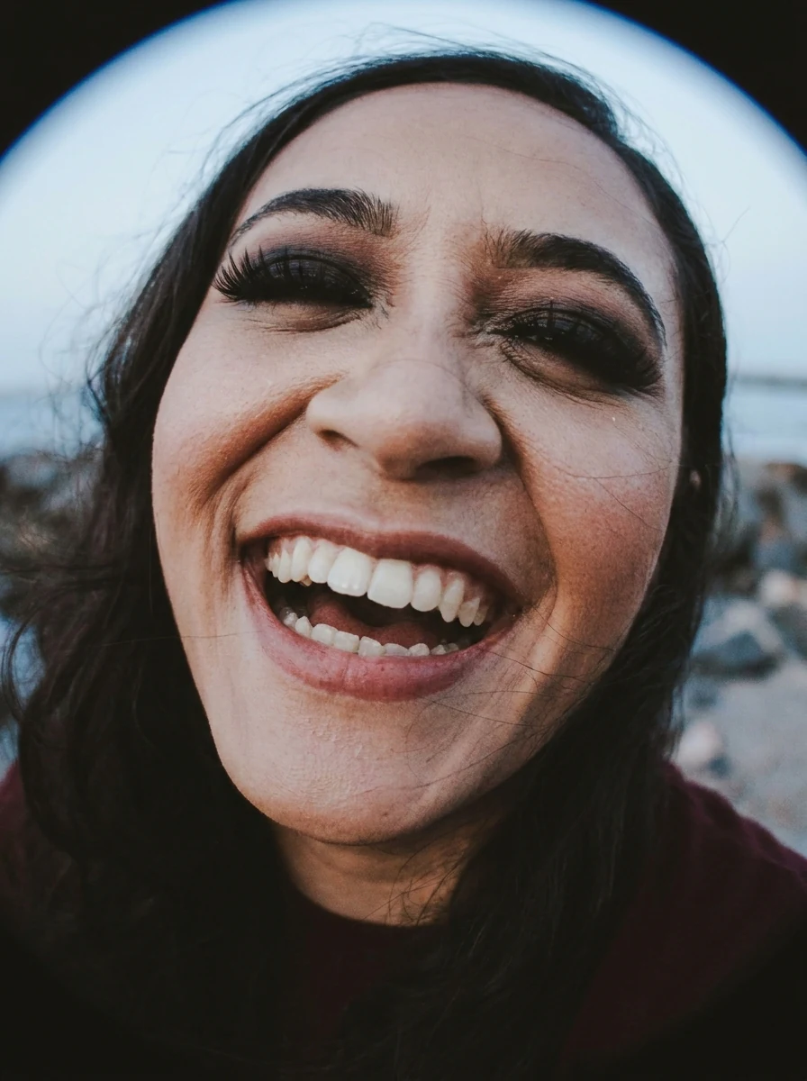 Fisheye effect selfie of a laughing woman with strong barrel distortion and a large face in the center