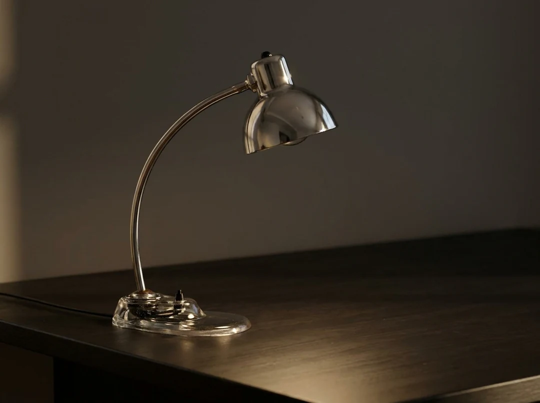 The desk lamp from the reference placed on an uncluttered dark desk with soft light from the left