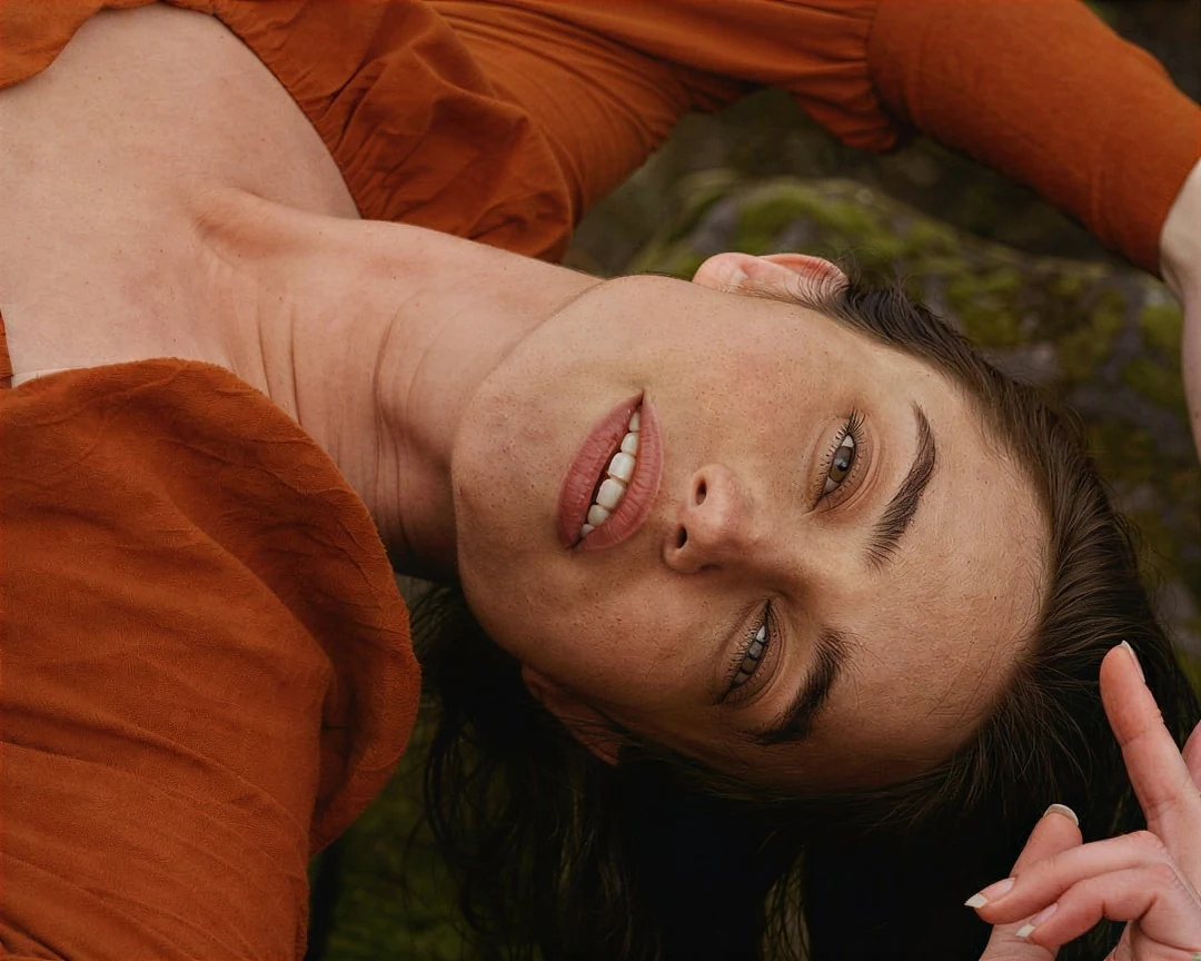 A portrait of a woman lying on grass